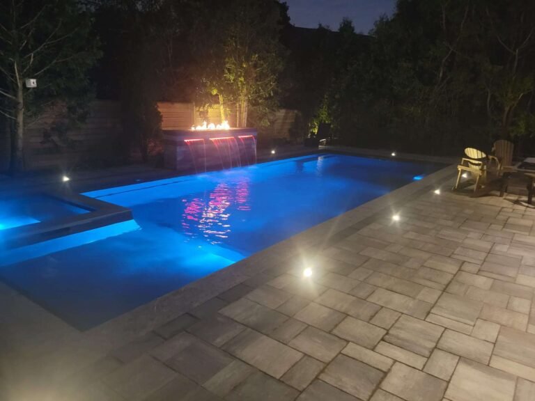 Custom inground pool in Newmarket with soft evening lighting and lush landscaping.